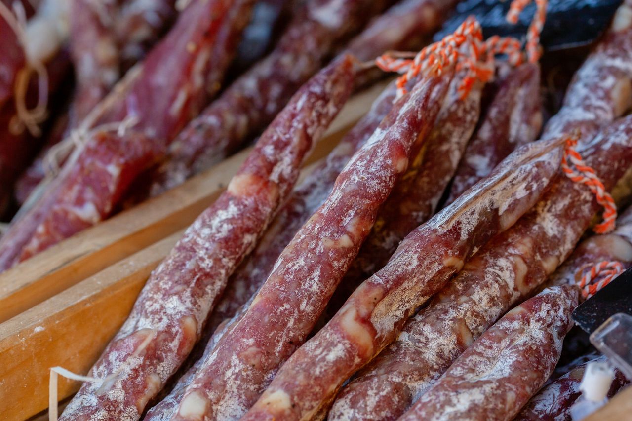 A detailed close-up of traditional Italian salami sticks arranged in rows, showcasing their texture.